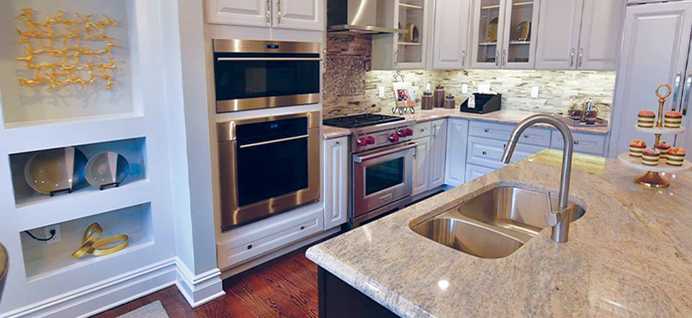 Interior shot of a kitchen showing a double wall oven, center island with double sink, and plenty of counter space